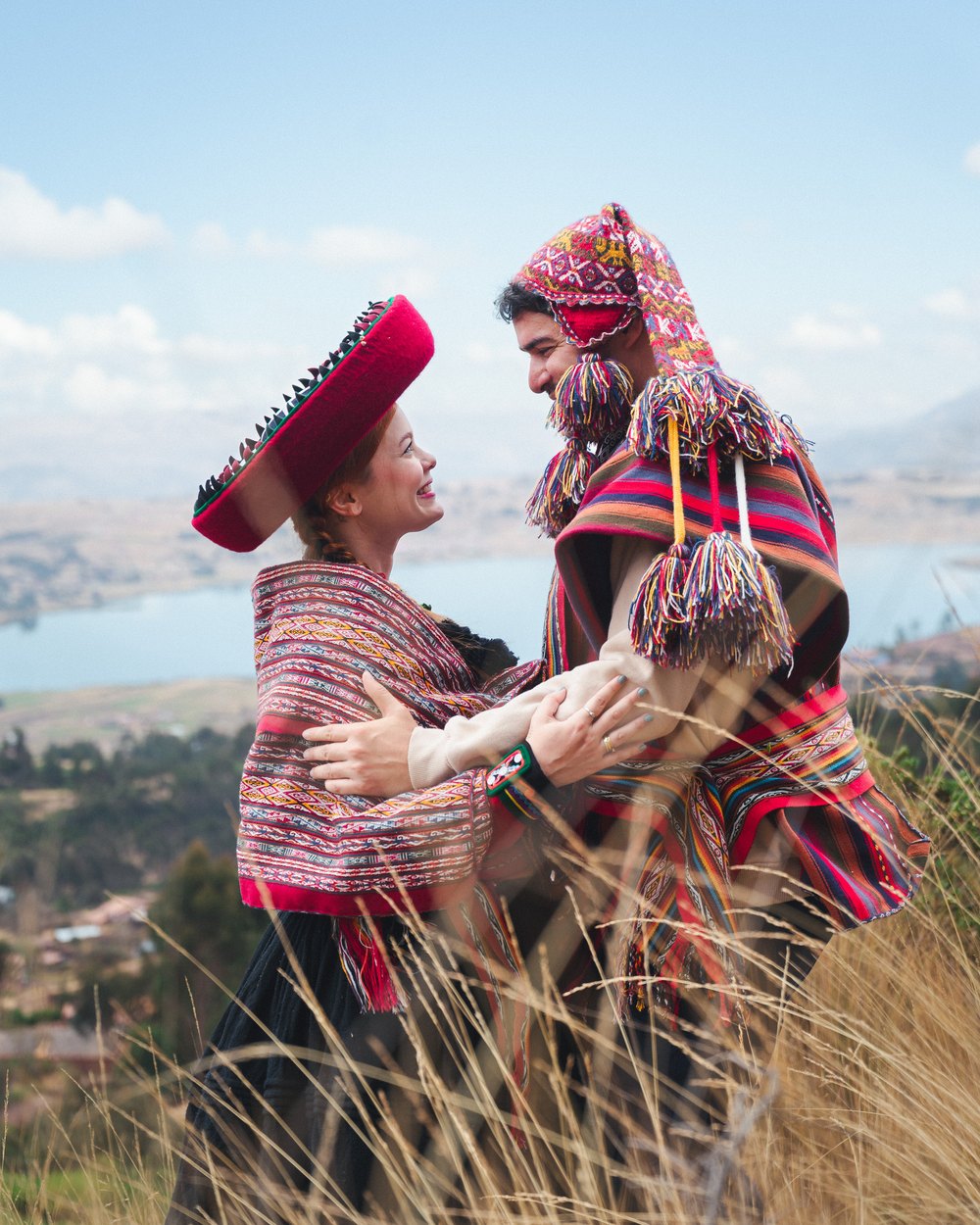 Bride and groom in Andean dress embrace on a hillside above the Sacred Valley